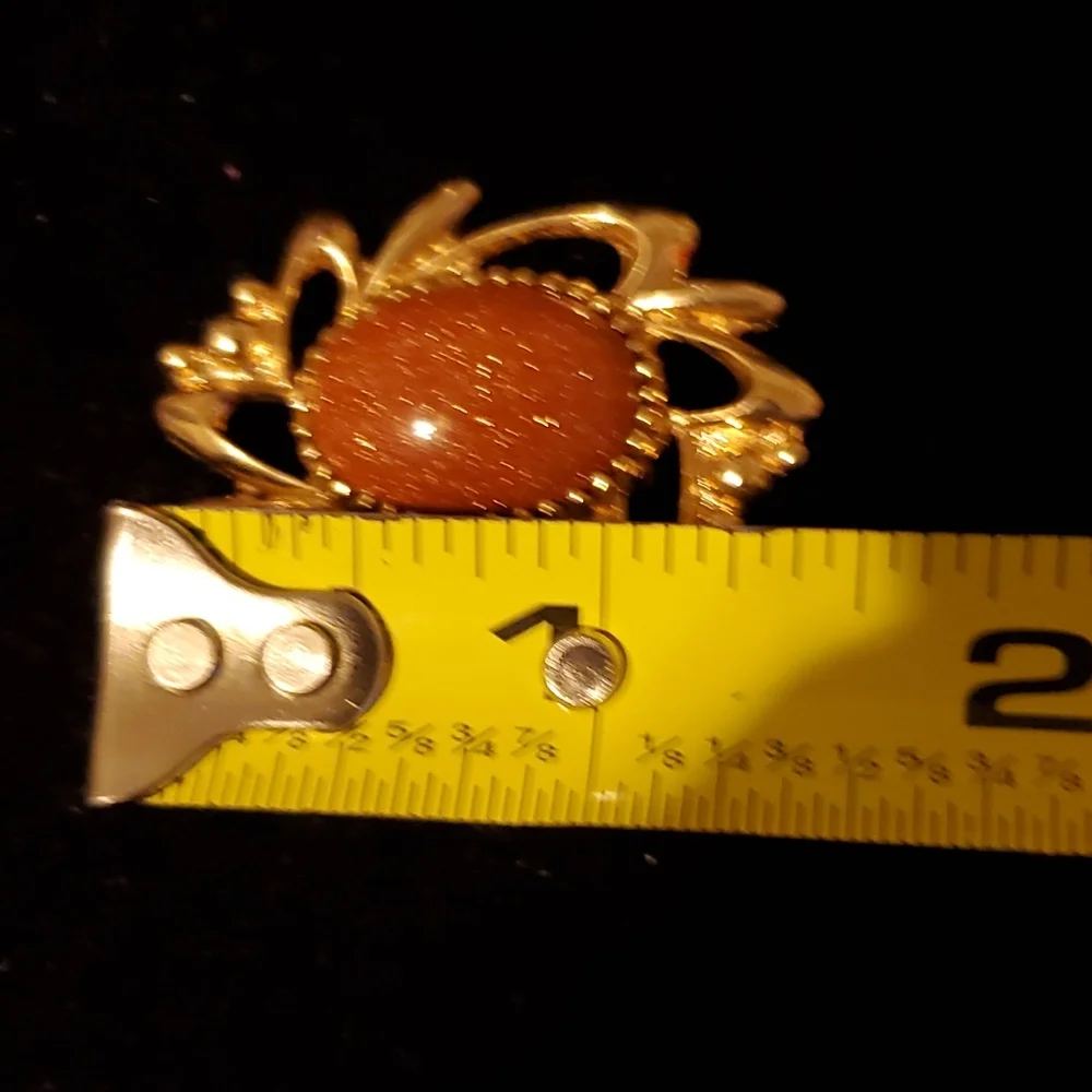 Goldtone brooch with rust colored glittery center stone